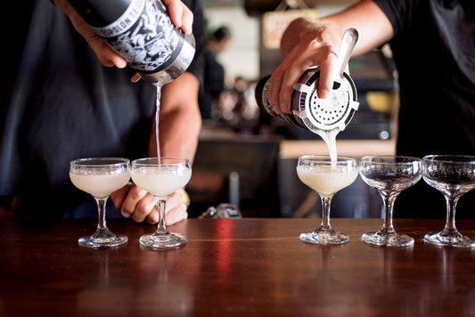 bartenders pouring alcoholic drinks at bar