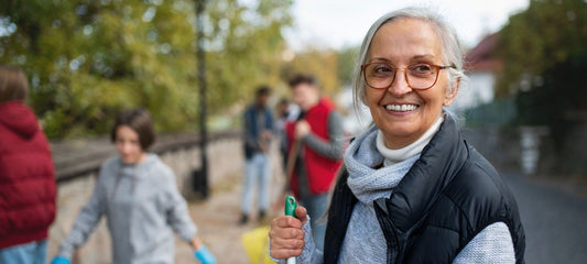 smiling senior woman volunteering and cleaning up street
