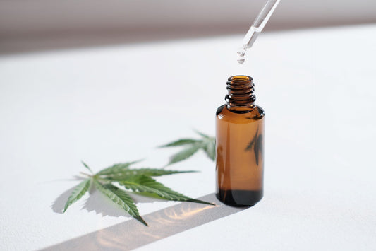 CBD oil for seniors on white table surrounded by cannabis leaves