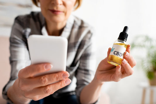 senior woman holding bottle of cbd