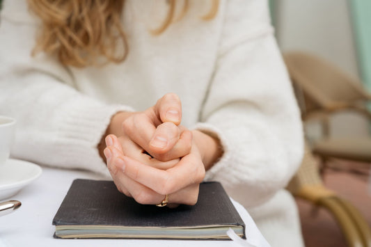 senior woman sitting in cafe holding hands anxiously