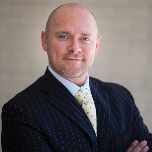 Charles warner CEO, Media Executive and 55plus CBD advisory board member in a suit with a patterned tie against a neutral background