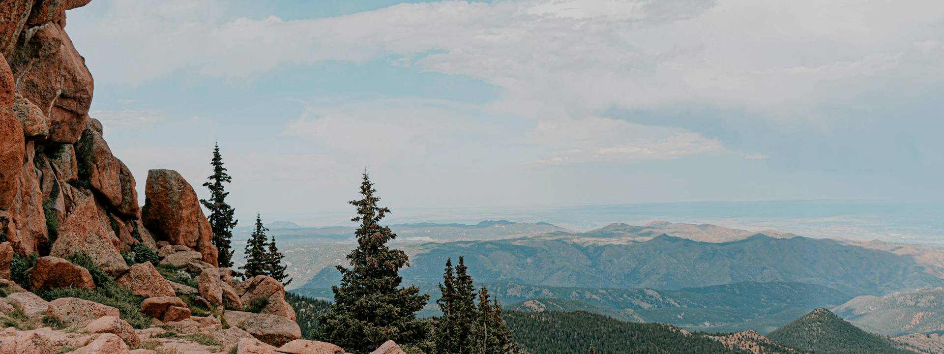 Scenic view of mountains with rocky cliffs and trees under a cloudy sky in colorado.