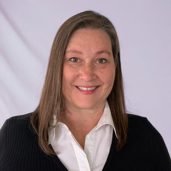 Dr. Karen Cino certified natural health practitioner, MS-nutrition, Master herbalist, and 55plus CBD medical advisory board member wearing a black sweater over a white shirt against a light gray background